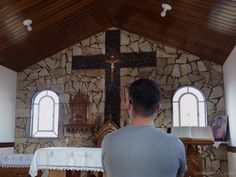 a man standing in front of a stone wall with a cross on it's side