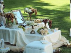 the table is covered with white cloths and decorated with flowers, plants and other things