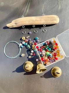 beads, bells and other items are on the ground next to a piece of wood