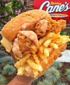 someone holding up a chicken sandwich with fries in front of a game's sign