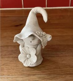 a small white gnome figurine on a wooden table with red tiles in the background