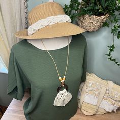 a woman's green shirt and hat sitting on top of a wooden table next to a potted plant