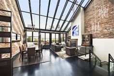 a living room filled with furniture and a fire place under a glass ceiling covered in windows