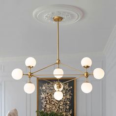 a chandelier hanging from the ceiling in a room with white walls and paintings