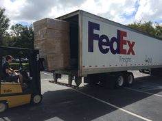 a man driving a forklift next to a fed ex truck