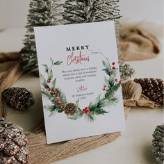 a christmas card sitting on top of a table next to pine cones and other decorations