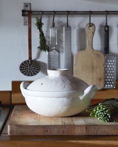 a large white bowl sitting on top of a wooden table next to cutting boards and utensils