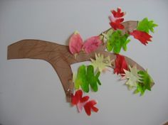 the paper flowers are attached to the wooden branch on the wall above the bed headboard