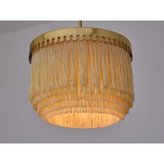 a chandelier with fringes hanging from it's ceiling and the light is on