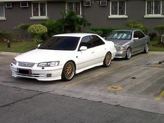 two white cars parked next to each other in a parking lot