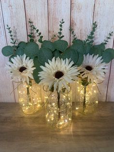 three mason jars filled with white flowers and greenery