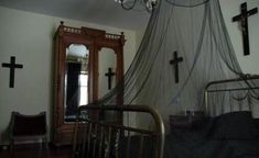 a crib with a cross hanging from it's side in front of a mirror