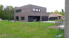 a large brick house sitting in the middle of a lush green field next to a fence