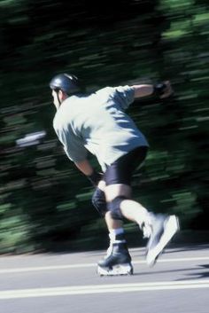 a man riding a skateboard down the side of a road next to a forest