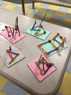 four pieces of art made out of construction paper on a table with scissors and pencils