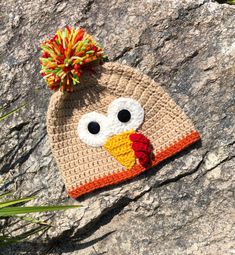 a crocheted turkey hat sitting on top of a rock