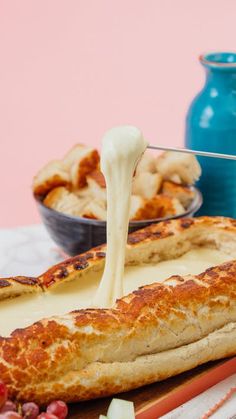 a piece of bread with cheese being drizzled over it on a plate