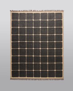 a black and white rug with squares on it, in the middle of a gray background