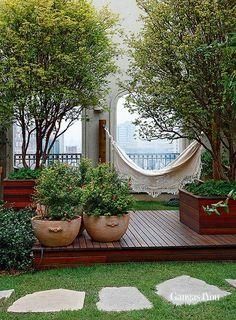 a wooden deck with potted plants on it and hammock in the background