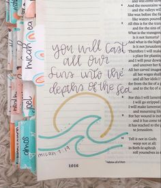 an open bible with writing on it and some crayon markers next to it