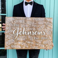 a man in a tuxedo holding up a wooden sign