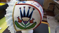 a white hat with designs on it sitting on top of a wooden headdress