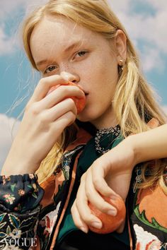 a woman is holding an apple and eating it