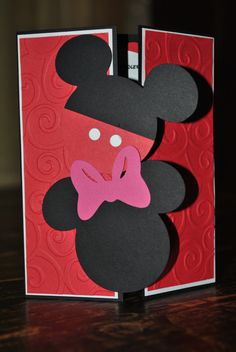 a mickey mouse card with a pink bow on it's head and red background