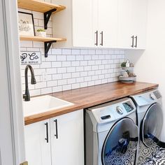 a washer and dryer in a small room with white cupboards on the wall