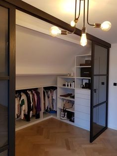 an open closet with lots of clothes hanging on the wall and lights in the ceiling