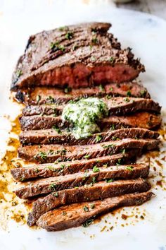 sliced steak on a plate with sauce and green garnish, ready to be eaten