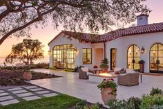 an exterior view of a house with large patio and seating area at sunset or dawn