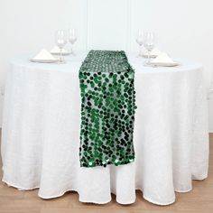 the table is set with white linens and green sequined napkins on it