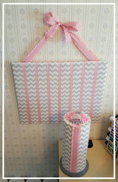 a pink and white cake with ribbon on top sitting next to a wallpapered background