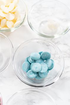 three bowls filled with different colored candies on top of a marble countertop next to each other