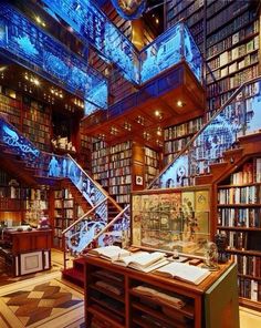 a library filled with lots of books next to a stair case covered in blue lights