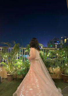 a woman in a wedding dress is standing on the balcony at night with her back turned to the camera