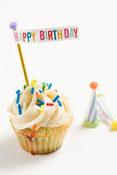 a cupcake with white frosting and sprinkles is next to a sign that says happy birthday