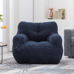 a blue bean bag chair sitting on top of a rug next to a gray couch