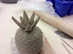 a clay pineapple sitting on top of a table next to a rolling pinwheel