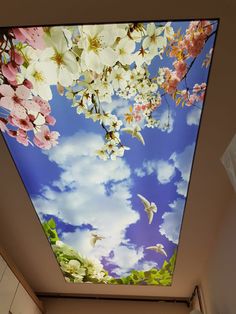 the ceiling is decorated with flowers and birds flying in the blue cloudy sky above it