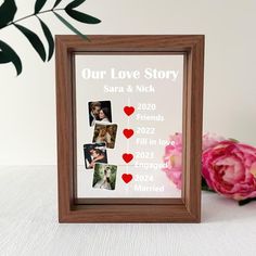 a wooden frame with photos and hearts on it next to a bouquet of pink flowers