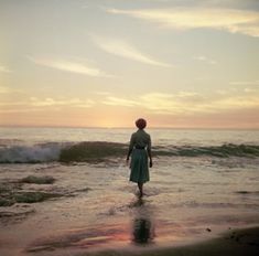 a woman standing in the ocean at sunset