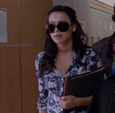 two people standing next to each other in front of lockers and holding folders