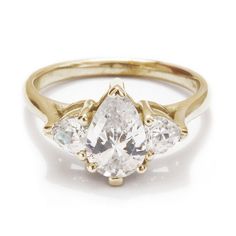 a pink diamond and three white diamonds in a gold ring with two pears on the side