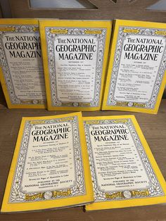 three books sitting on top of a wooden table next to an open book with information about the national geographic magazine