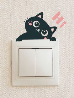 a black cat sitting on top of a light switch