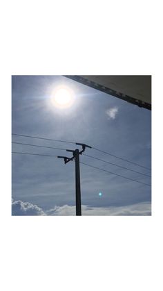 the sun shines brightly behind power lines and telephone poles in front of a blue sky