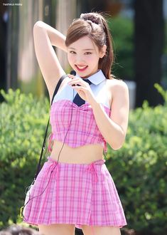 a young woman in a pink dress posing for the camera with her hand on her hip