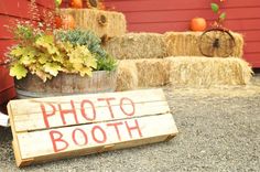 a wooden sign that says photo booth next to hay bales with pumpkins in the background